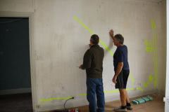 Mick giving John a lesson on how to rewire the house, drawing maps on all the wall's